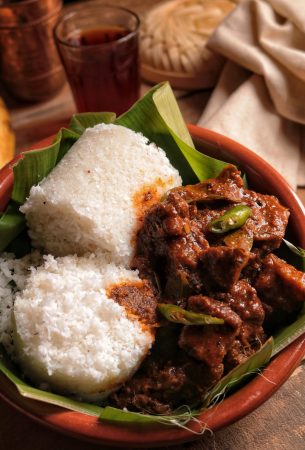 Delicious Indian dish featuring beef curry and puttu served in a clay pot on a banana leaf.