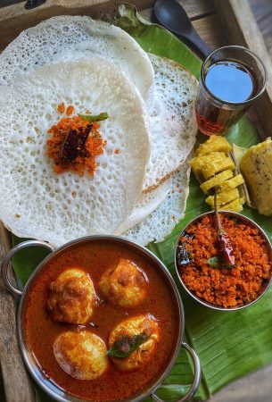 Delicious South Indian breakfast served on a banana leaf with appam, curry, and chutney.